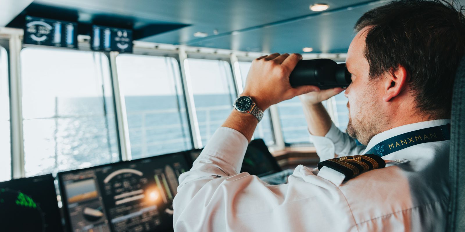 An officer uses binoculars to scan the horizon from the bridge of Manxman, the flagship RoPax ferry of the Isle of Man Steam Packet Company