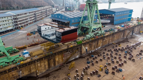 Section of a ferry in shipyard being built with crane behind it