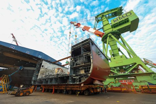 Section of a ferry in shipyard being built with crane behind it