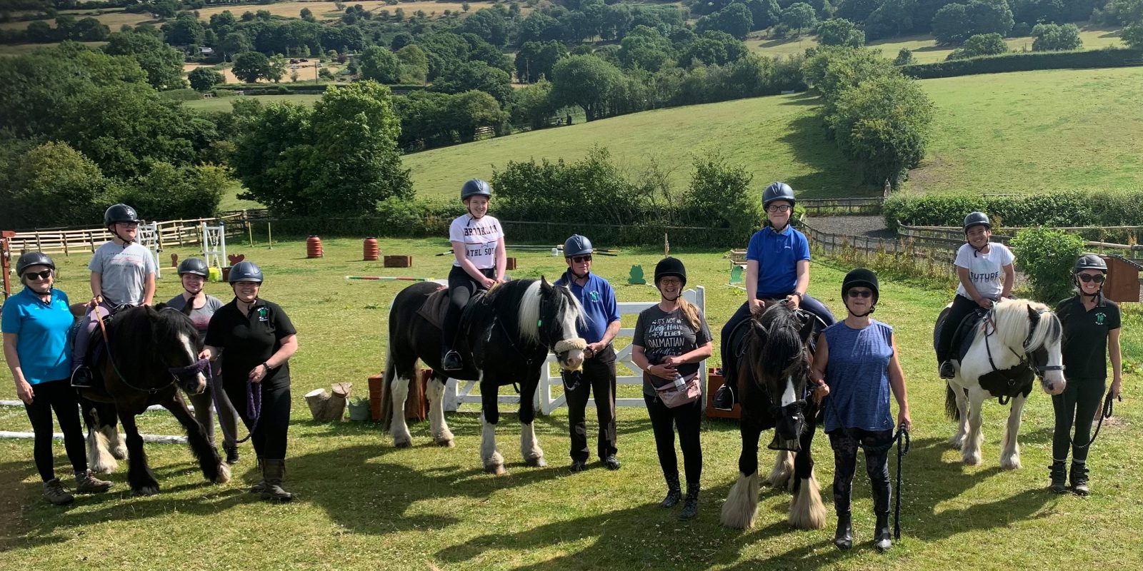 Children on horses with adult instructors in a field in the sun