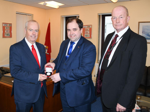 Two men presenting Isle of Man coin issued in 1979 to mark the Millennium of Tynwald to another man