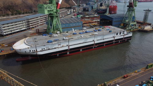 Ferry in shipyard being built with cranes around it in the sea