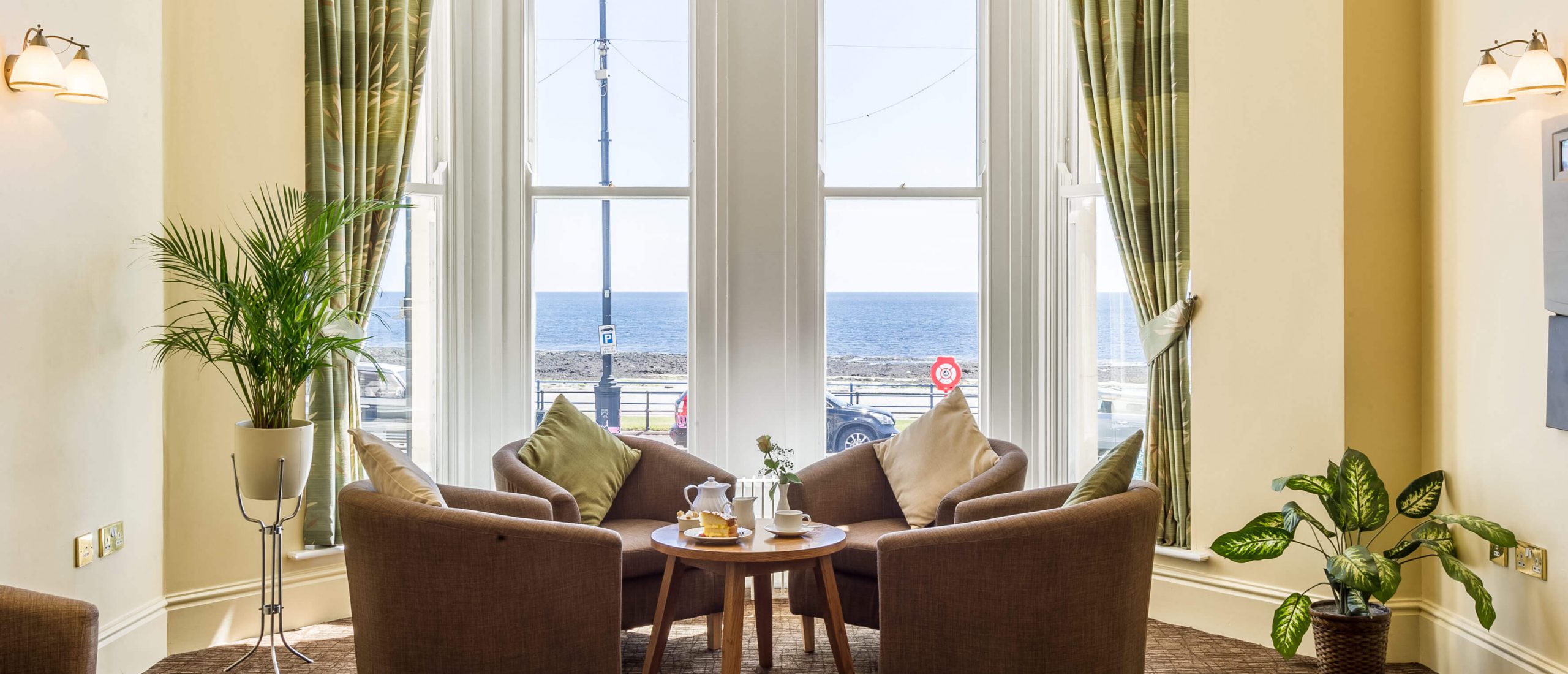 View from inside a hotel with seats and tea and cake out to the sea