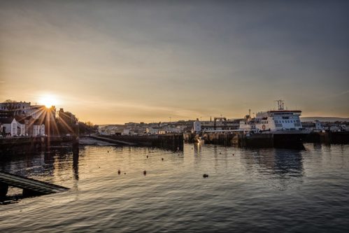 Sunset of a harbour with a ferry leaving to go out to sea